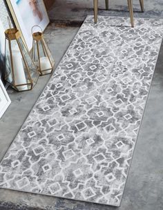 a white and gray rug with an intricate design on the floor next to two chairs