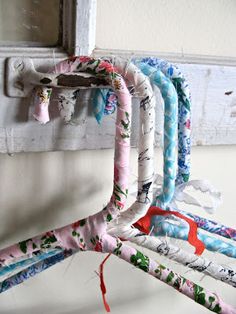 an old window frame is decorated with colorful fabric and some scissors hanging from it's hooks