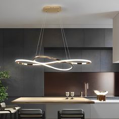 a modern chandelier hanging over a kitchen island in a house with black walls