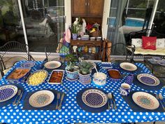 a blue and white table topped with lots of food next to a patio area covered in polka dots