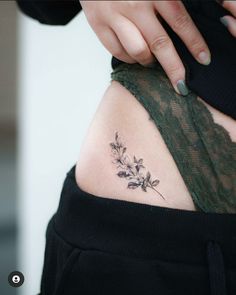 a woman's stomach with a small flower tattoo on her left side ribcage