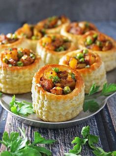 several small pastries on a plate with parsley sprinkled around them and garnished with peas