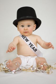 a baby wearing a new year's sash sitting on top of a white table