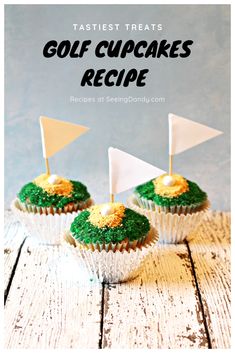 three cupcakes with green frosting and white flags on top, sitting on a wooden table