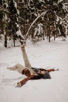 a woman laying in the snow with her legs spread out and head down on her back