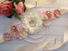 a close up of flowers and pearls on a white table cloth with ribbons around it