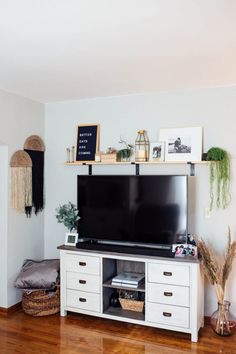 a flat screen tv sitting on top of a white entertainment center next to a wooden floor