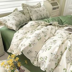 a bed with white and green sheets, pillows and blankets on top of the bed