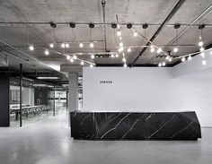 an empty room with black and white marble counter top in the center, surrounded by lights