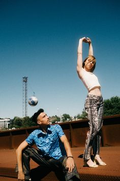 a man and woman playing with a ball on a tennis court