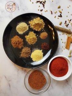 various spices are arranged in bowls on a marble counter top next to an empty bowl