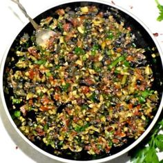 a pan filled with food sitting on top of a white table next to parsley