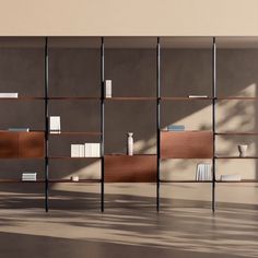 a book shelf with many books on it in the middle of an empty room next to a window