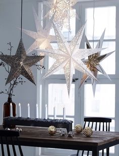 a table topped with lots of stars hanging from it's ceiling next to candles