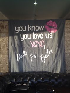 a black leather couch sitting in front of a banner