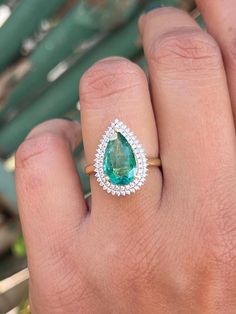 a person's hand with a ring on it and a green stone in the middle