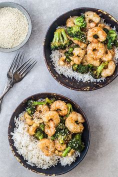 two bowls filled with shrimp and broccoli on top of white rice next to a fork