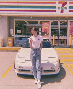 a woman standing in front of a car holding a drink