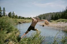 a man is jumping into the water with a hat on his head and arms in the air