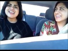 two women are sitting in the back seat of a car and one is looking at the camera