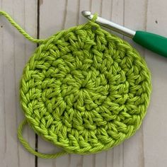 a crochet potholder with a green handle and yarn in the middle next to it