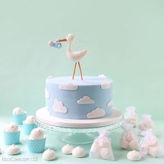 a baby shower cake with cupcakes and a stork figurine on top