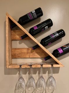 four wine glasses are hanging from a wooden shelf