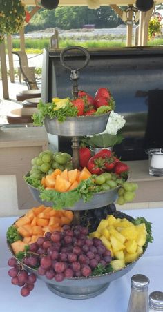 a three tiered platter filled with fruit and vegetables