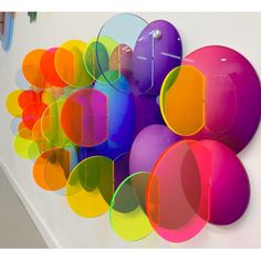 an art piece is hanging on the wall in front of a group of colorful balloons