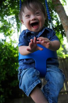 a young boy sitting on top of a blue swing