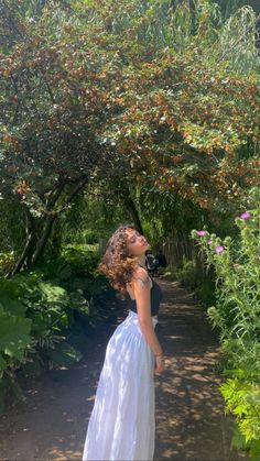 a woman in a white dress standing under a tree