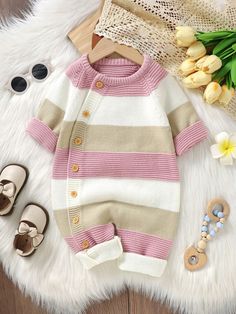 a baby's striped sweater and shoes are laid out on a white fur rug