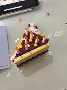 a lego cake with candles on it sitting on a table next to a cell phone