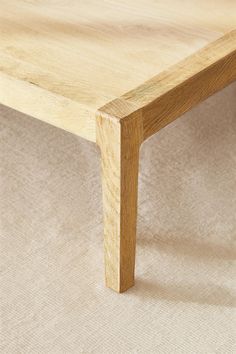 a wooden table sitting on top of a beige carpeted floor next to a white wall