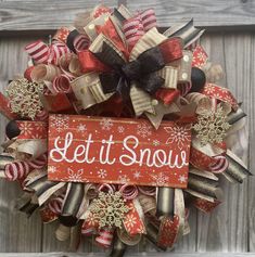 a christmas wreath with the words let it snow on it and bows attached to it