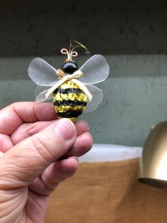 a hand holding a tiny yellow and black bee