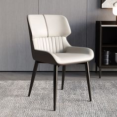 a white chair sitting on top of a rug next to a book shelf and lamp