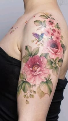 a woman's shoulder with flowers and leaves painted on her left arm, which is covered in tattoos