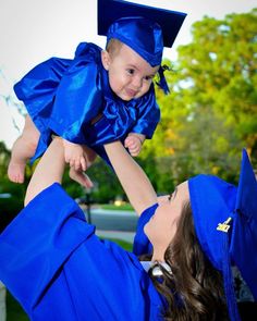 a woman holding a child in her arms while wearing blue graduation caps and gowns