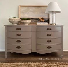 a dresser with two bowls on top of it and a lamp in front of it