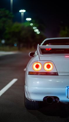 the back end of a white sports car at night