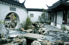 an outdoor garden with rocks and water features in the center, surrounded by white buildings