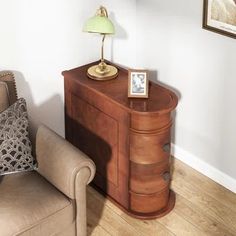 a chair sitting next to a wooden cabinet with a lamp on it's side