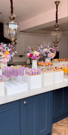 a kitchen counter topped with lots of desserts and flowers on top of it's counters