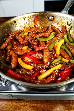 a pan filled with meat and peppers on top of a stove