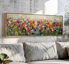 a painting hanging on the wall above a couch in front of a potted plant