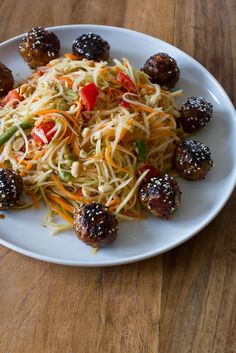 a white plate topped with meatballs and veggies on top of a wooden table