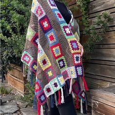 a woman is wearing a crocheted shawl in the shape of granny's squares