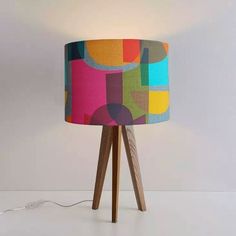 a lamp that is sitting on top of a wooden table next to a white wall