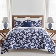 a blue and white bed in a bedroom with two lamps on either side of the bed